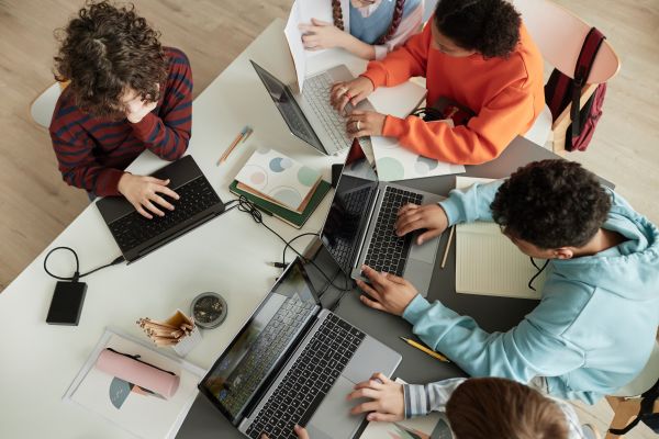 Students using computers work together at table