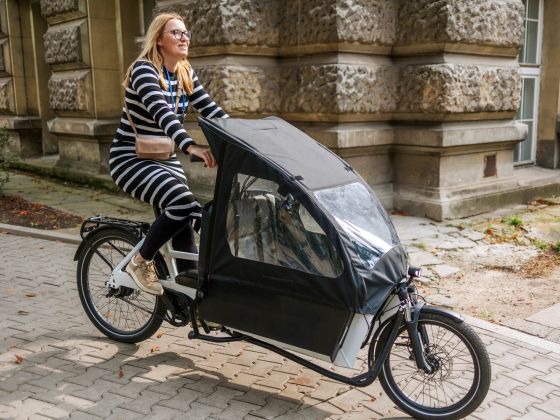 A young woman rides a cargo bike through the city.